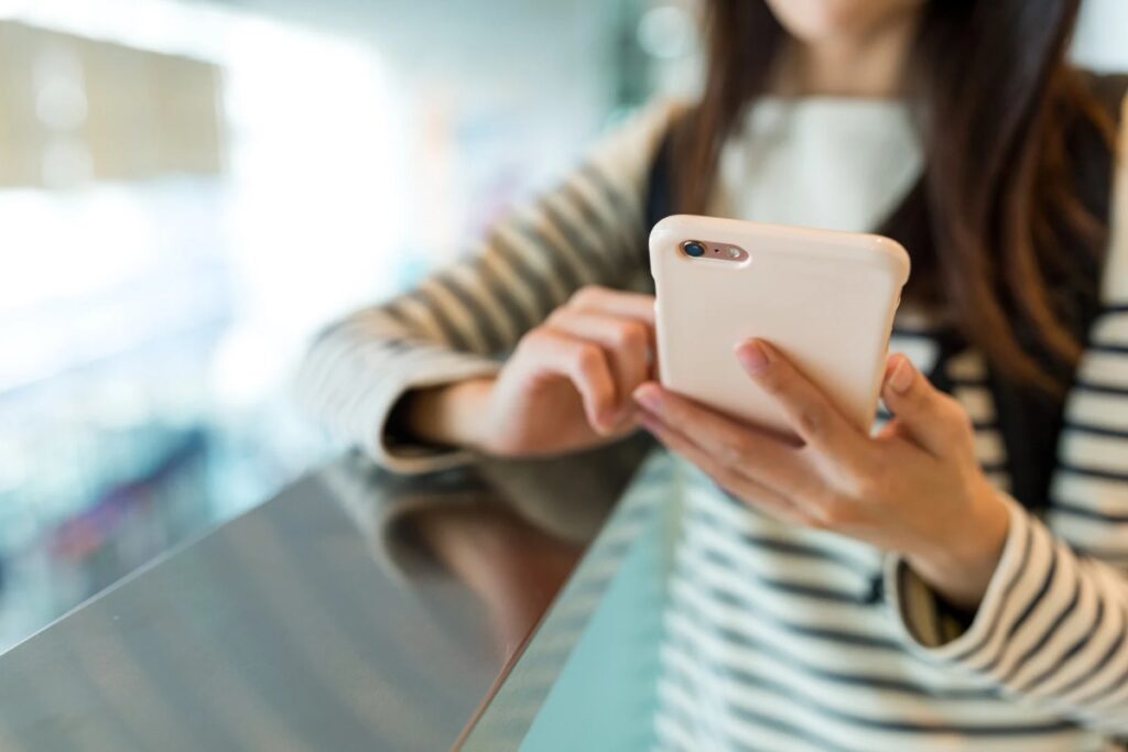 Mulher aplicando estratégias para economizar internet no celular em local público